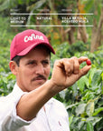 Man holding a coffee cherry in a coffee farm setting
