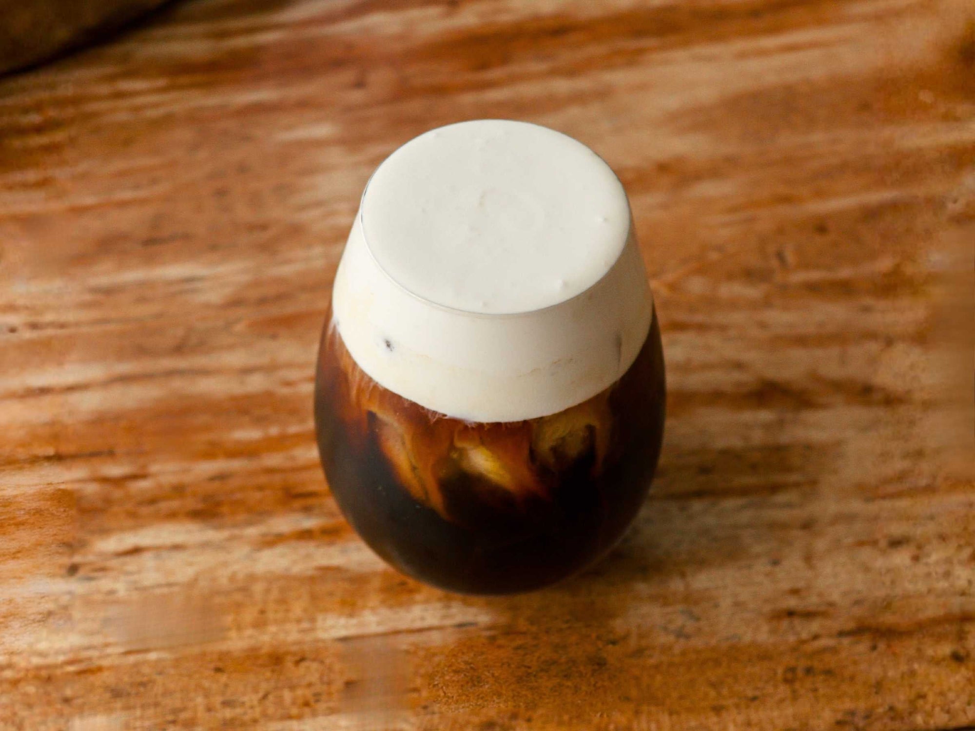 A glass of cold brew coffee with cold foam on top
