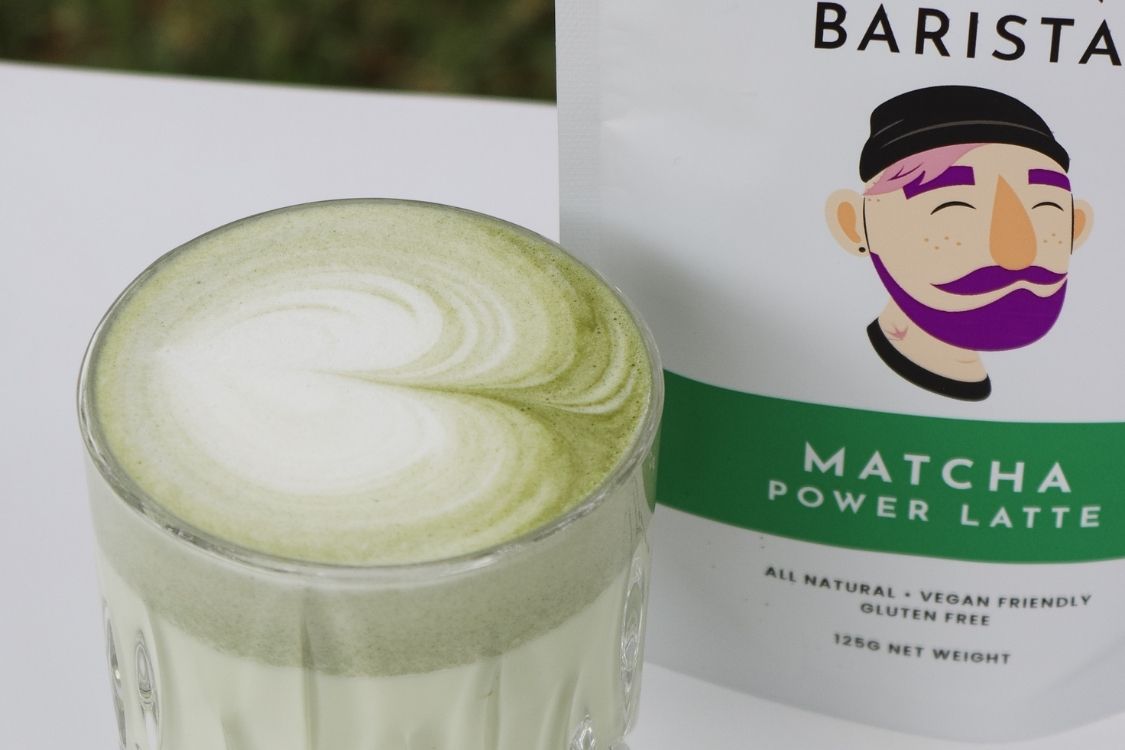 A cup of Matcha Latte next to a bag of Matcha Latte Mix