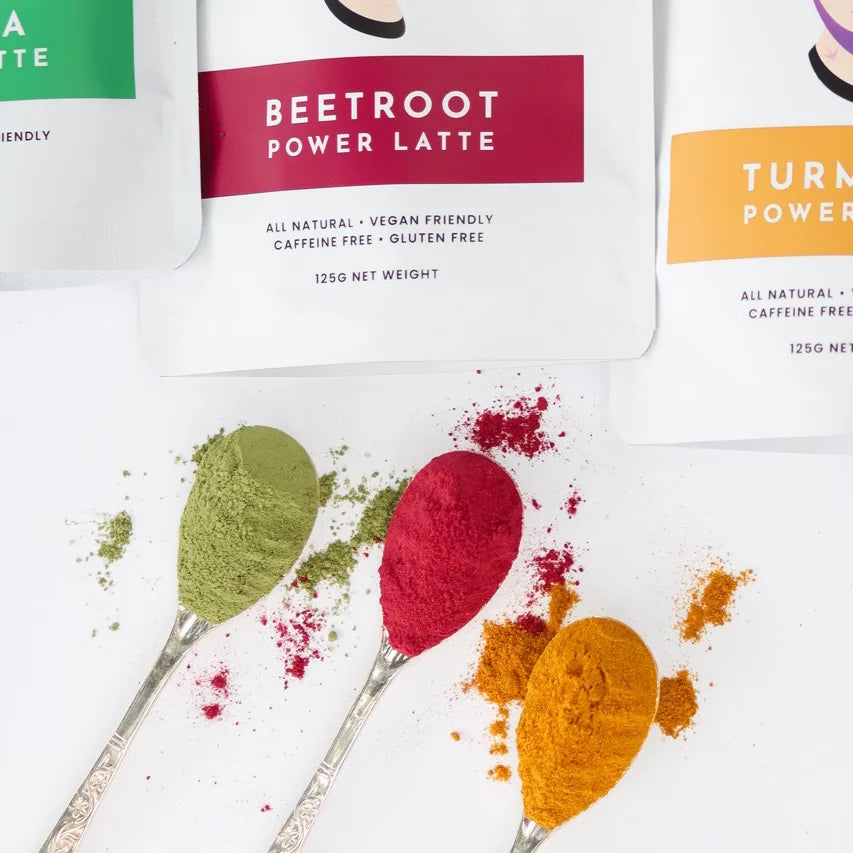 Matcha, turmeric and beetroot latte mixes on spoons on white background