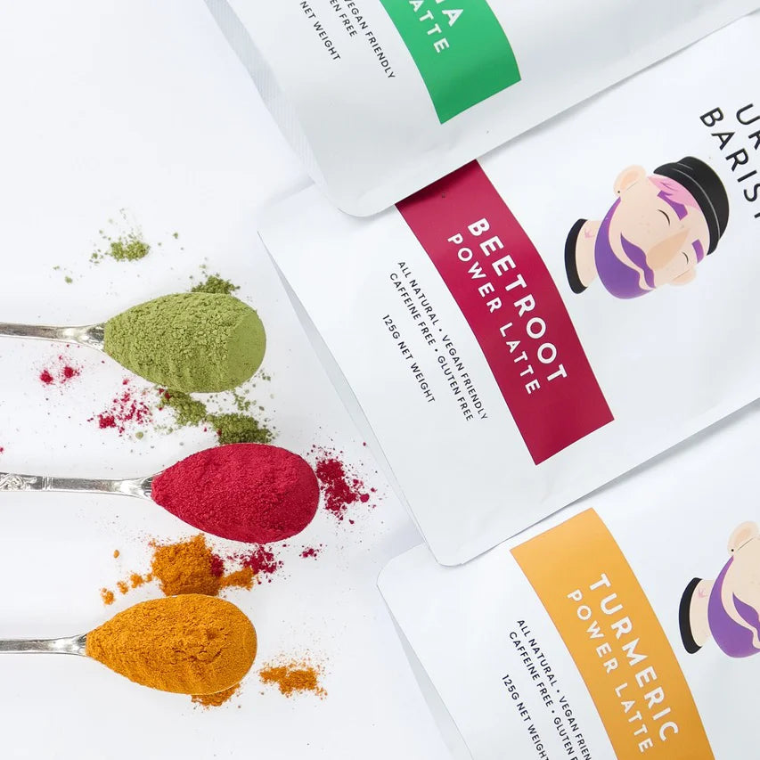 Beetroot, turmeric, and matcha powders on teaspoons with packaging