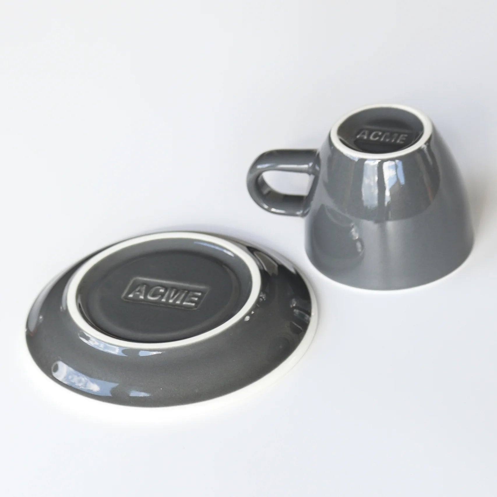 ACME grey ceramic cup and saucer on a white background