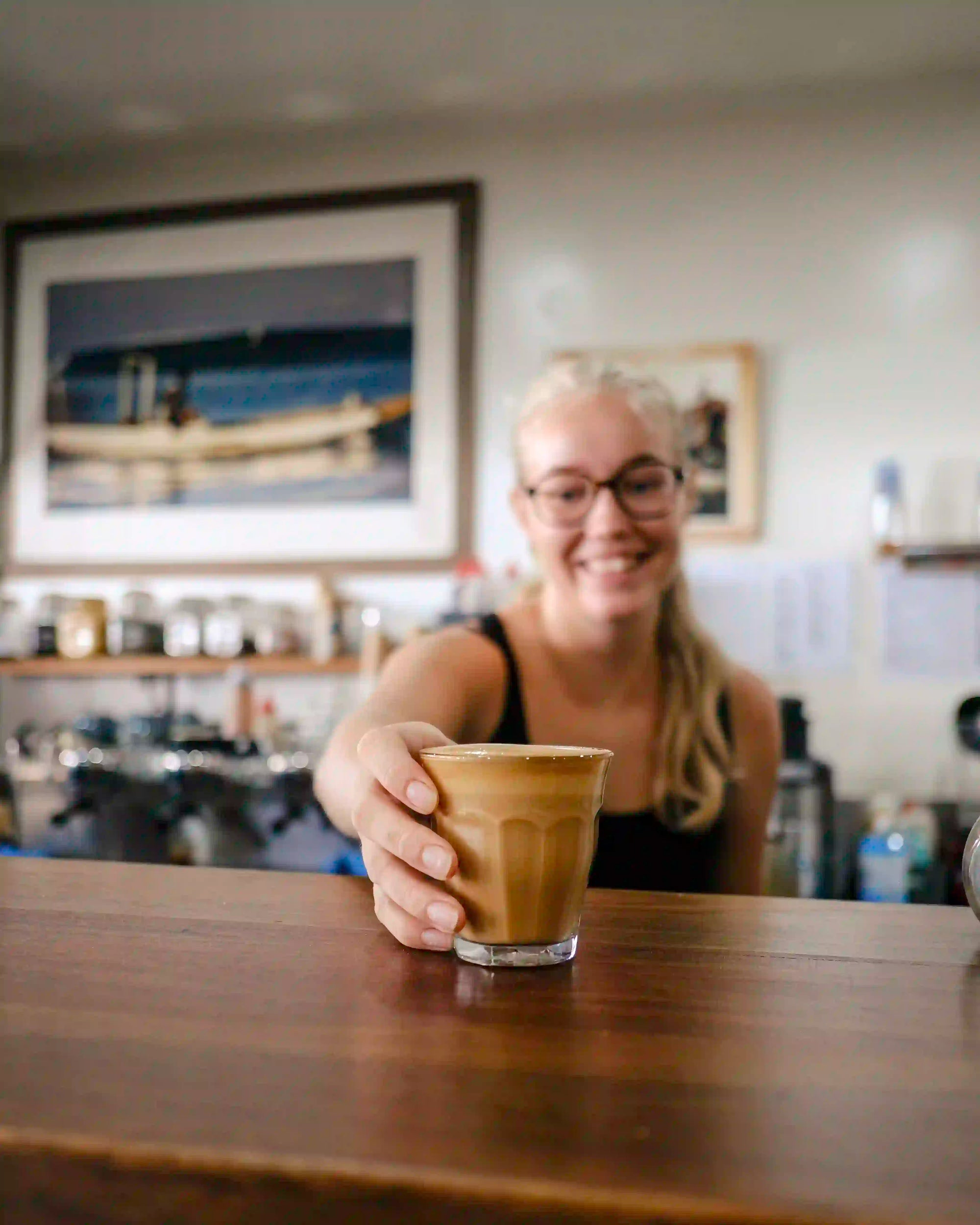 Smiling woman serving a latte in a coffee shop