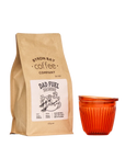 A 500g bag of Dad Fuel coffee next to an Amber Huskee Coffee Cup