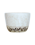 Ceramic coffee cup with speckled design and leaf pattern on a white background