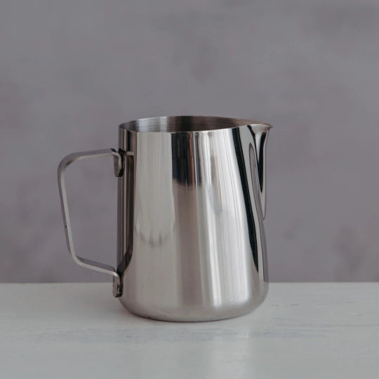 Stainless steel milk jug on a grey background