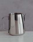 Stainless steel milk jug on a grey background