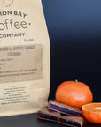 Bag of Colombian single origin coffee for filter next to tangerines and little blocks on Turkish delight